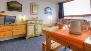 A cozy room with a wooden desk, a television, a cabinet, and a window with a view of the water.