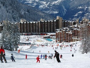 A ski resort with multiple buildings, a ski slope, and a pool area.