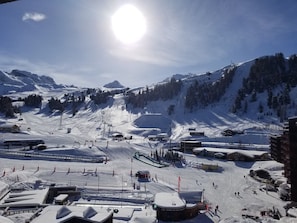 Uma estação de esqui com encostas cobertas de neve, teleféricos e edifícios.