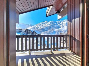 Ein Balkon mit Blick auf schneebedeckte Berge und ein Gebäude im Hintergrund.