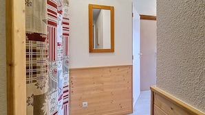 Un pasillo con paneles de madera, un espejo y una puerta.