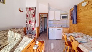 Un espacio habitable compacto con sofá, mesa de comedor y kitchenette.