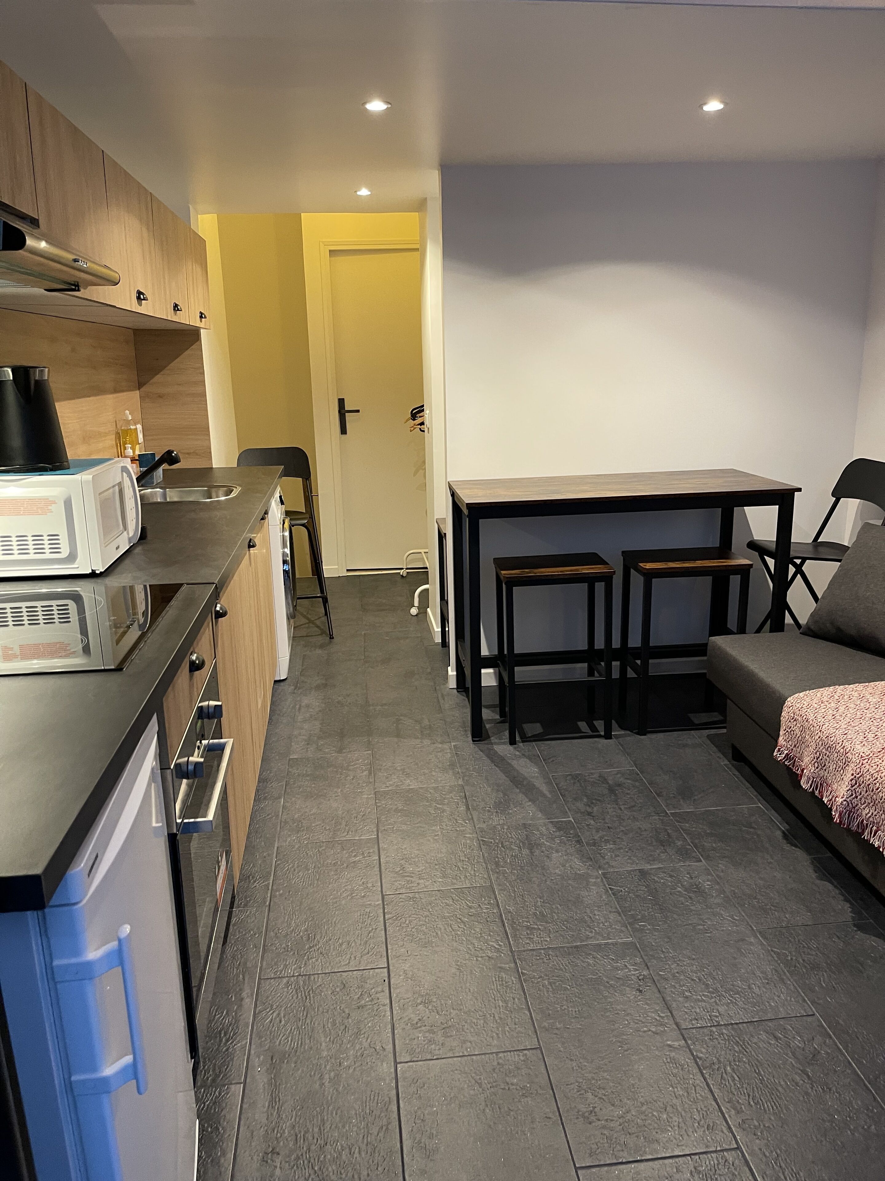 A compact kitchen with modern appliances, a dining area with a table and chairs, and a sofa.