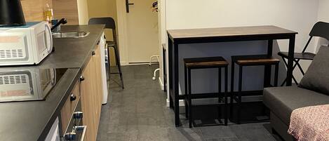 A compact kitchen with modern appliances, a dining area with a table and chairs, and a sofa.