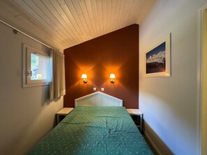 A room with a bed, two bedside tables, a window with curtains, and two wall-mounted lamps. - Renovated apartment, ski-in/ski-out, pets allowed (Belle Plagne)