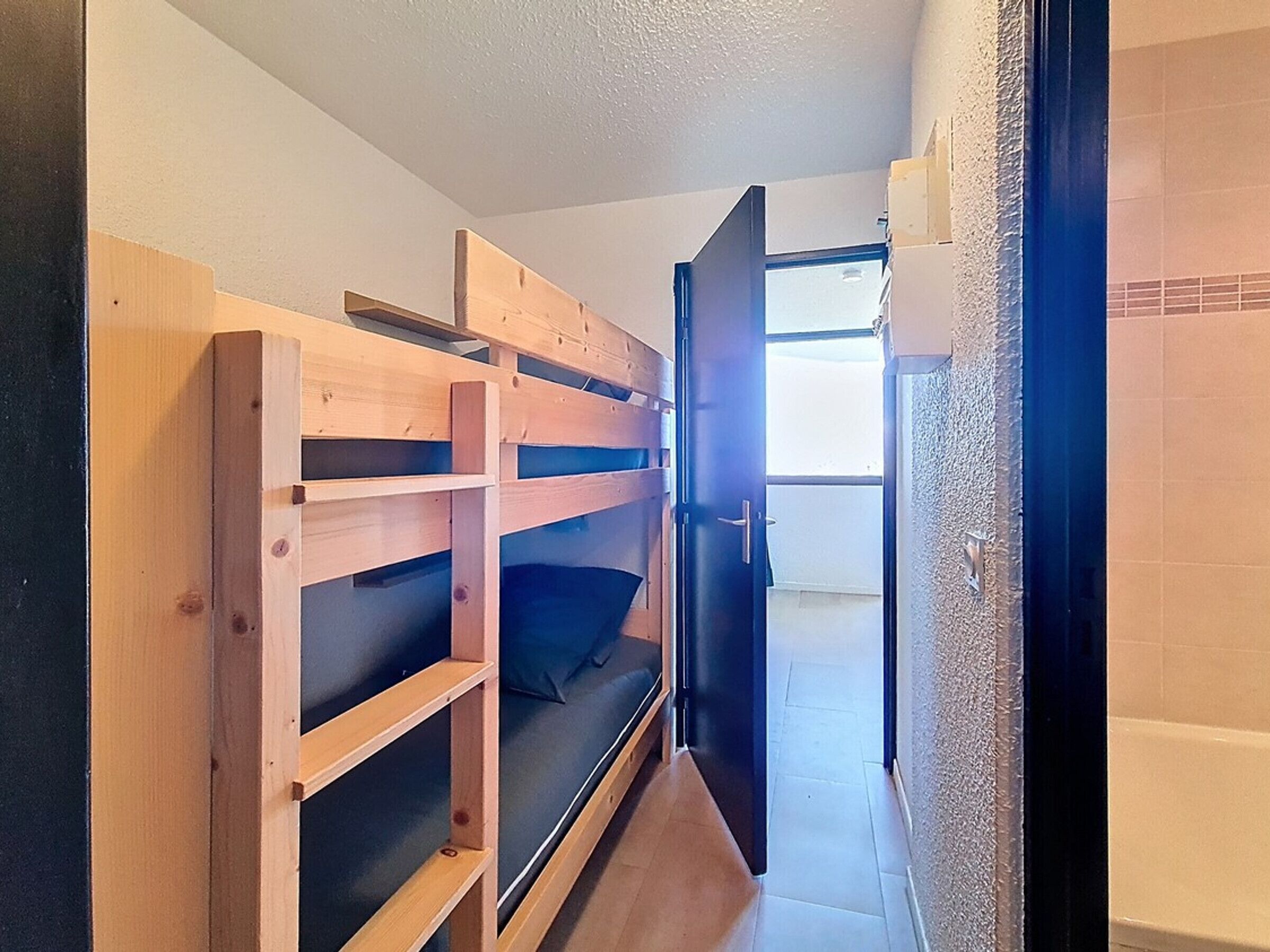 En smal gang med køjesenge og en dør, der fører ud til en balkon.