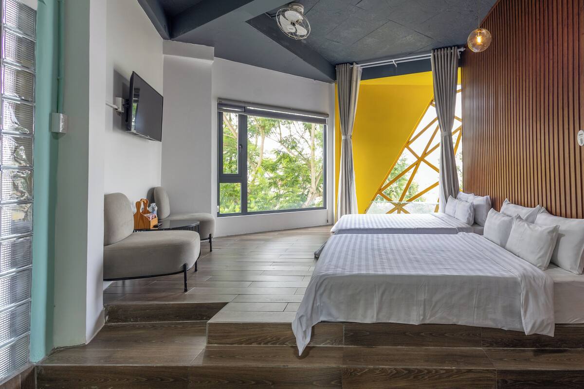 Une chambre moderne avec un lit, une chaise, un téléviseur et une fenêtre donnant sur des arbres.
