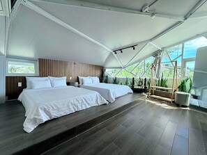 Une chambre moderne avec deux lits, une tête de lit en bois, une grande fenêtre et une vue sur la verdure.