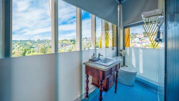 A bathroom with a large window, a wooden vanity, a toilet, and a towel rack.