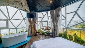Ein modernes Zimmer mit einem großen Bett, einer Badewanne und einem Tisch mit Stühlen.