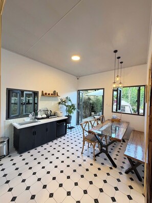 A modern kitchen with a dining area, black and white hexagonal floor tiles, and large windows.