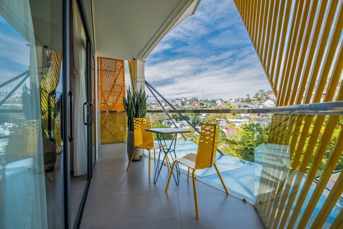 Un balcon doté d’une balustrade en verre, d’une table et de deux chaises.