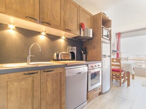 A modern kitchen with wooden cabinets, stainless steel appliances, and a dishwasher. - Functional studio near shops and slopes, south-facing balcony, 4 people, non-smoking (La Rosière)