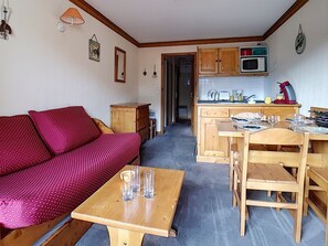 Un espacio habitable compacto con sofá, mesa de comedor y zona de cocina.