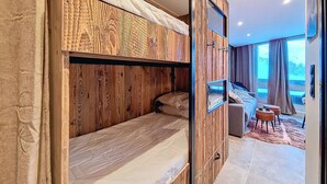 Una habitación moderna con literas, una pequeña zona de estar y un amplio ventanal con vistas.