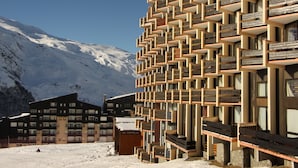 Un edificio moderno con una fachada geométrica distintiva, ubicado en una zona montañosa nevada.