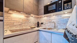 Una cocina moderna con salpicadero de piedra, electrodomésticos de acero inoxidable y horno empotrado.