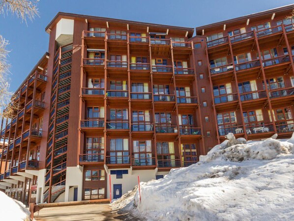 A multi-story hotel with balconies, a fire escape, and a snow-covered ground.