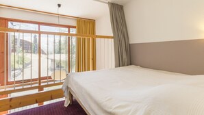 Une chambre avec une grande fenêtre, un lit et une vue sur l’extérieur.