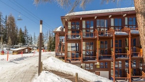 Un immeuble en bois à plusieurs étages, doté de balcons, entouré de neige et d’arbres.