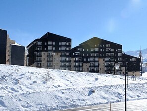 Um edifício moderno de vários andares com varandas, localizado numa encosta nevada.