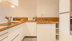 A modern kitchen with white cabinets, a wooden countertop, a built-in sink, and a coffee maker. - Spacious 4-room apartment in station center with balcony for 8 people (Les Arcs 1800)