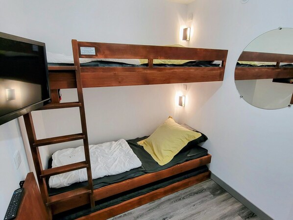A bunk bed with a ladder, a television, and wall-mounted lights.