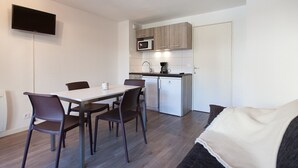 A compact living space with a dining area, kitchenette, and a sofa.