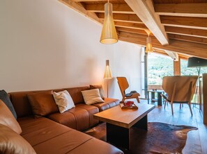 Un salon chaleureux avec un canapé en cuir marron, une table basse en bois et un coin repas comprenant une chaise et une table.