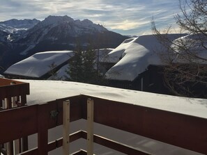 A snow-covered mountain landscape with a wooden deck and a metal railing.