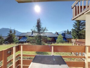 A wooden deck with a view of a mountain range and buildings with blue roofs.