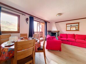 Uma sala de estar acolhedora com um sofá vermelho, mesa de jantar de madeira e lareira.