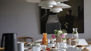 Tavola per la colazione apparecchiata con diversi piatti, una brocca e oggetti decorativi.