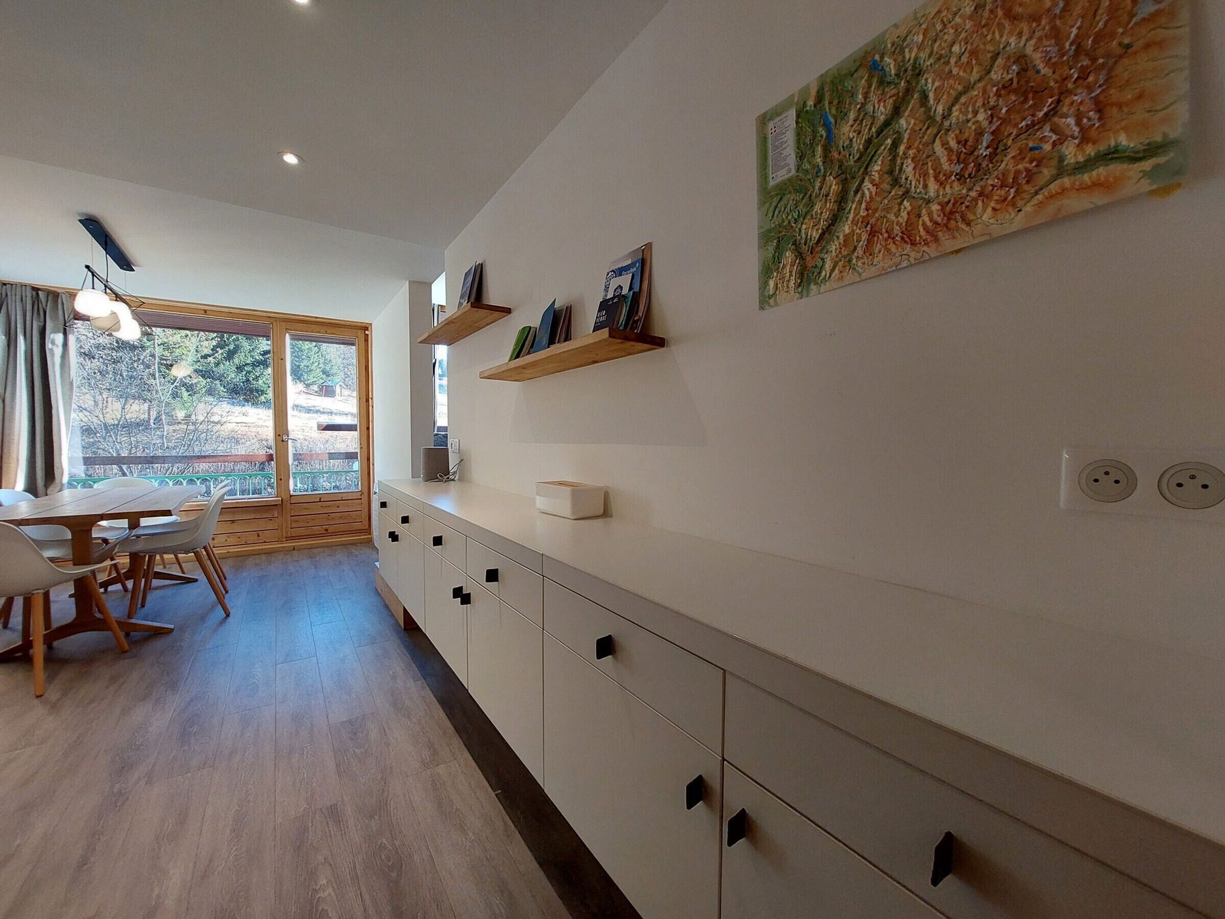 Een moderne keuken met witte kastjes, houten aanrecht en een eethoek met tafel en stoelen.