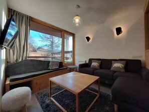 A cozy living room with a sofa, a wooden coffee table, and a window with curtains. - Renovated apartment, ski-in/ski-out, balcony, 7 people, WIFI (Les Arcs 1800)