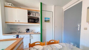 Eine kompakte Küche mit Mikrowelle, Spüle und einer kleinen Essecke mit Tisch für zwei Personen.