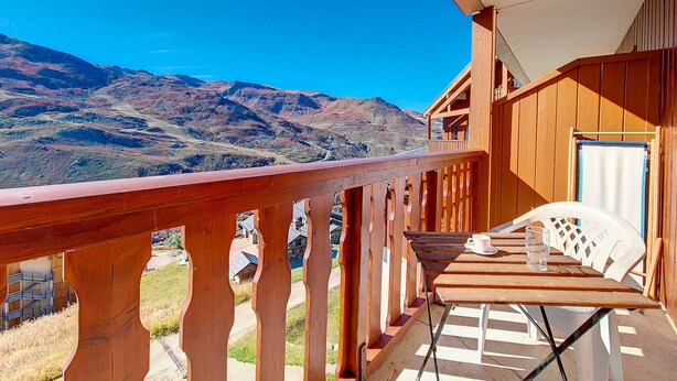 Ein Holzbalkon mit Tisch und Stühlen mit Blick auf eine Berglandschaft.