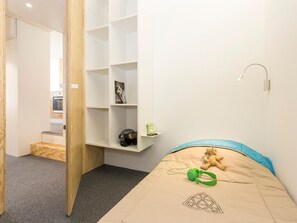 A bedroom with a bed, a shelf with a helmet, and a teddy bear.