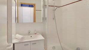 Een badkamer met een witte wasbak, spiegel en douche.