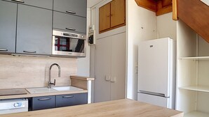 A compact kitchen with grey cabinets, a built-in microwave, a sink, and a white refrigerator. - Bright ski-in/ski-out duplex, 8 pers., 3 bedrooms, Les Menuires (Les Menuires)