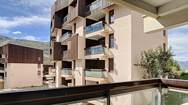 A modern apartment building with balconies, a stone pathway, and a view of the mountains. - Spacious apartment 6 pers. Near slopes with parking (Les Menuires)