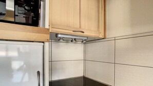 A compact kitchen with a built-in oven, a microwave, and a wooden cabinet above the oven. - Spacious apartment 6 pers. Near slopes with parking (Les Menuires)