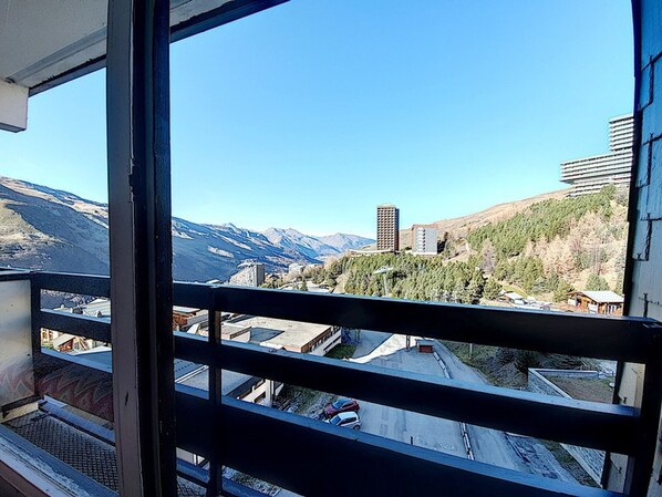 A balcony with a view of a mountainous landscape and buildings.