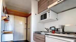 A compact kitchen with a microwave, coffee maker, and a small sink. There is a wooden shelf and a stool. - Cozy apartment for 4 with balcony at ski slopes (Les Menuires)