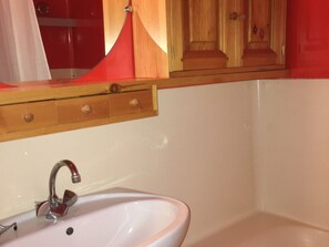 A bathroom with a sink, mirror, and cabinet.