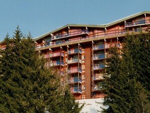 Standing amidst lush evergreen trees, this hotel features a unique curved roofline and balconies on each floor.