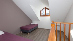 A small, sloped-roofed room with a single bed, a wooden railing, and a window. - Spacious chalet 8 pers, near slopes, Wifi, pets allowed (La Salle-les-Alpes)