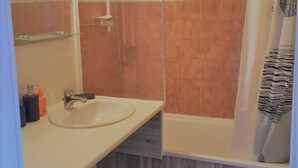 A bathroom with a sink, mirror, and shower.
