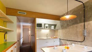 Een compacte keuken met een eethoek, met een magnetron, spoelbak en een tafel met stoelen.