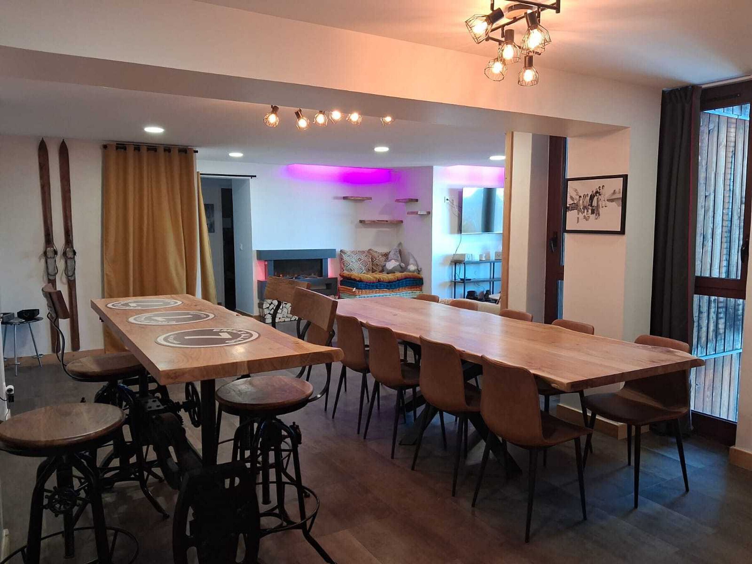 Een moderne eetruimte met een lange houten tafel en meerdere stoelen, een barstoel en een hanglamp.